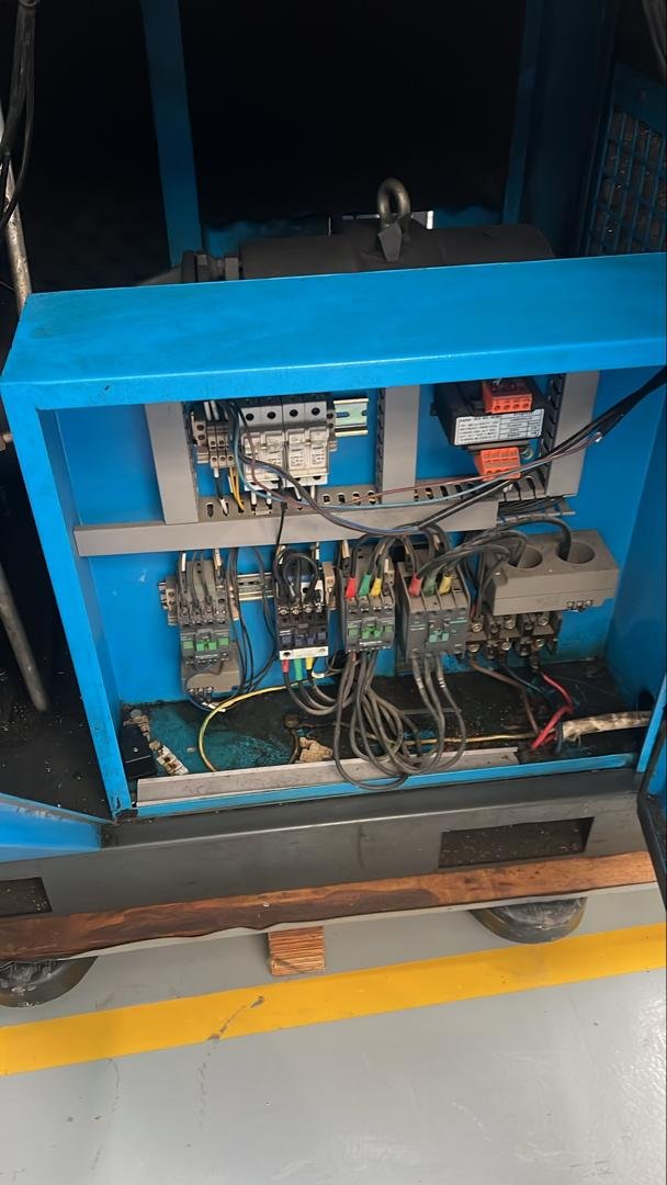Panel kawalan elektrik jentera industri sedang diselenggara, menunjukkan pendawaian dan komponen kawalan.